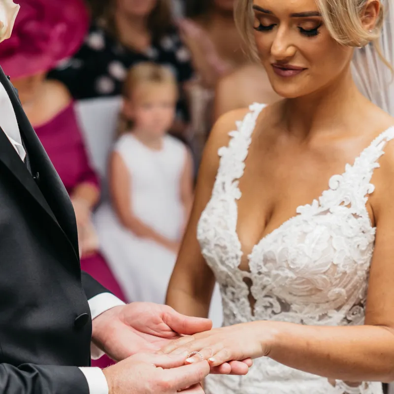 Groom placing a wedding ring on the bride's finger during a ceremony