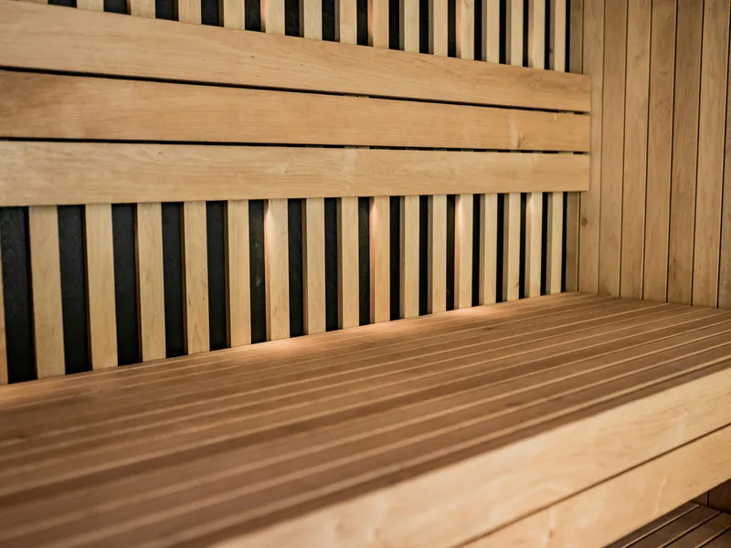 Close-up of a wooden sauna interior with slatted walls and a long bench.