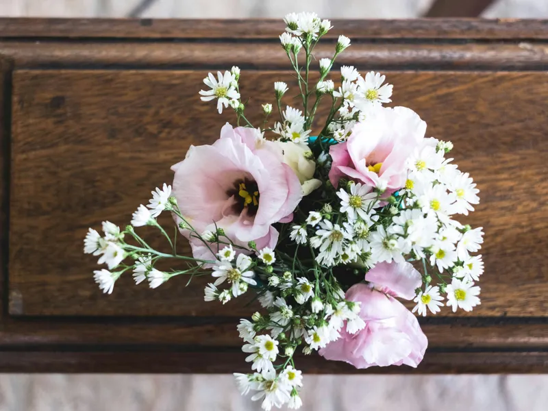 Delicate bouquet of pink flowers and white daisies on a dark wooden chair