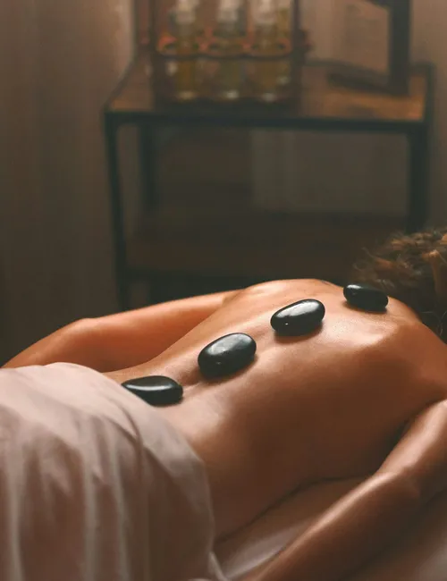 Person receiving a hot stone massage in a softly lit spa room