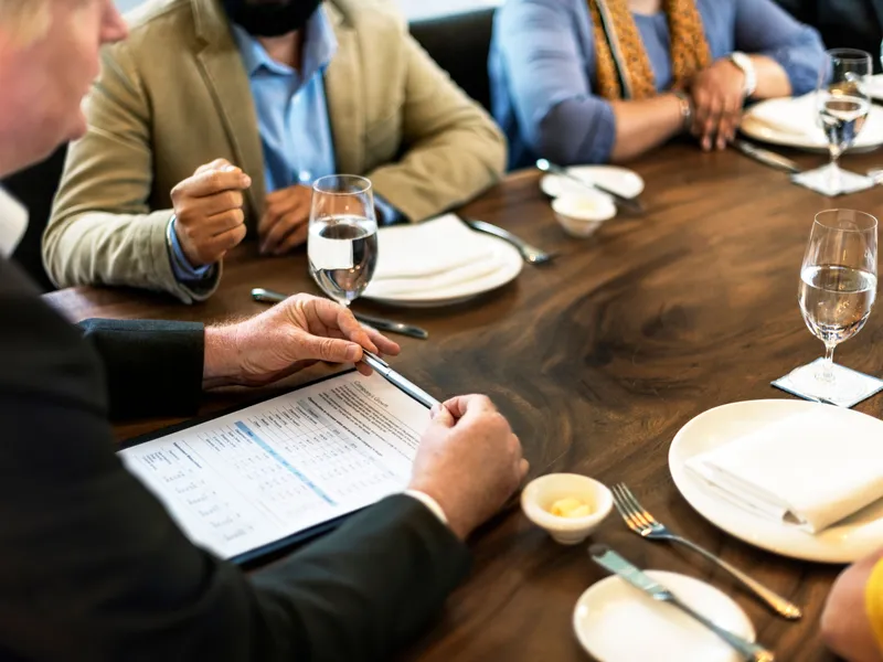 Businesspeople discussing a document around a restaurant table