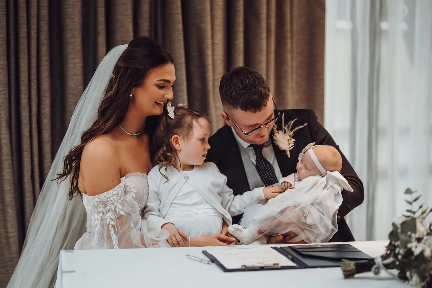 Bride and groom with two young children at a wedding signing table