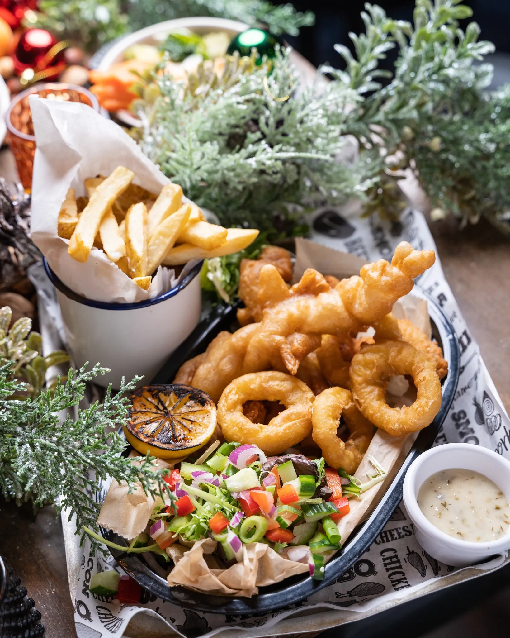 Basket of battered seafood with onion rings, chips, salad and dipping sauce