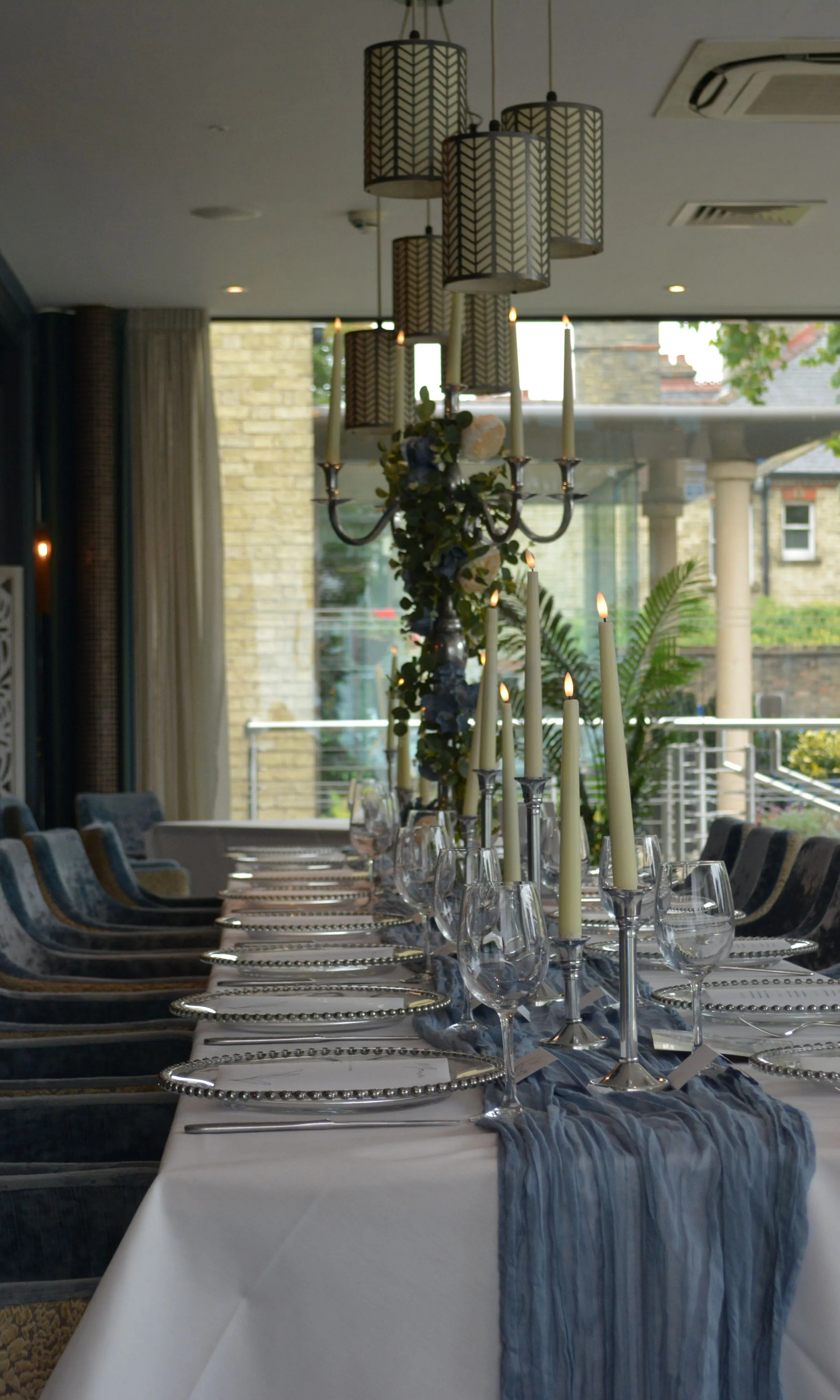 Elegant dining table set for a formal event in a stylish restaurant with velvet chairs and candles.
