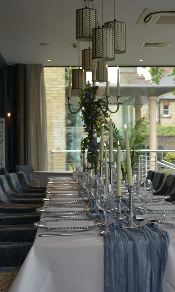 Elegant dining table set for a formal event in a stylish restaurant with velvet chairs and candles.
