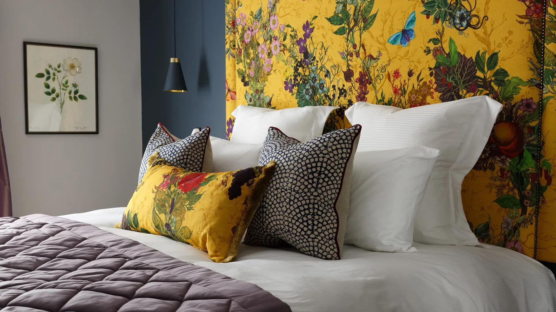 Rosa's stylish bed with white linens, decorative pillows, and a vibrant yellow floral headboard