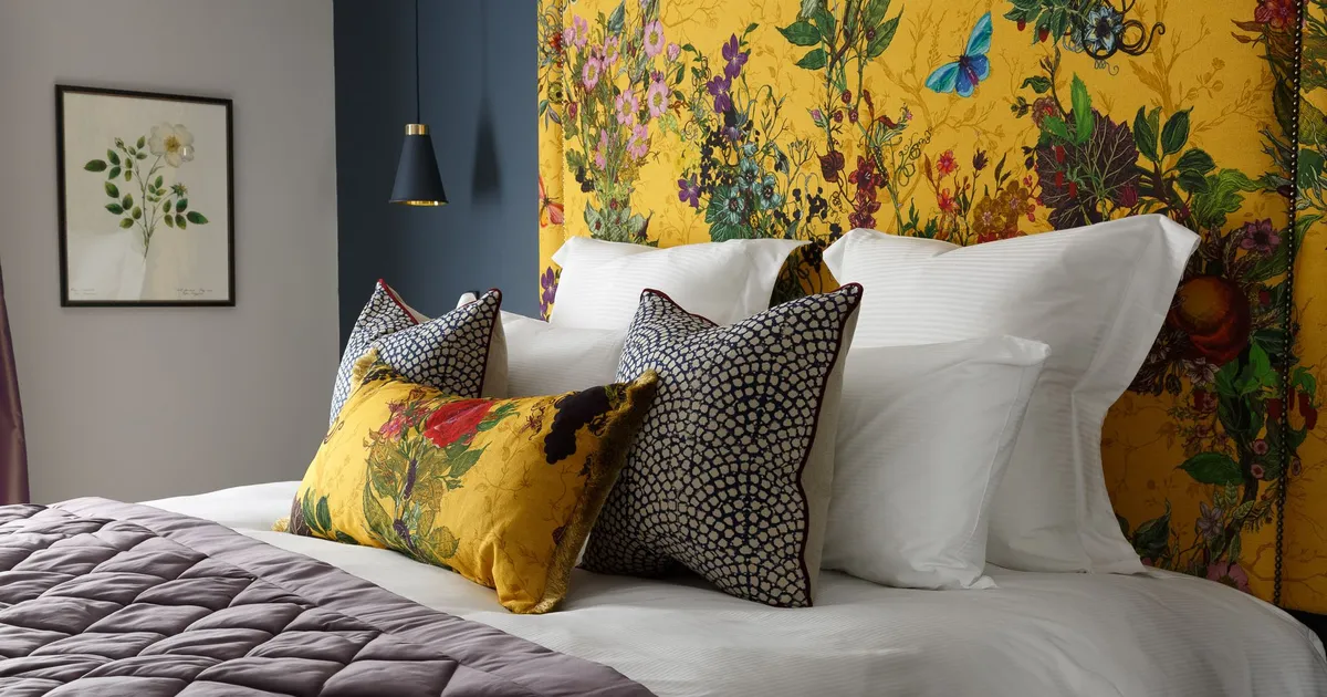 Rosa's stylish bed with white linens, decorative pillows, and a vibrant yellow floral headboard