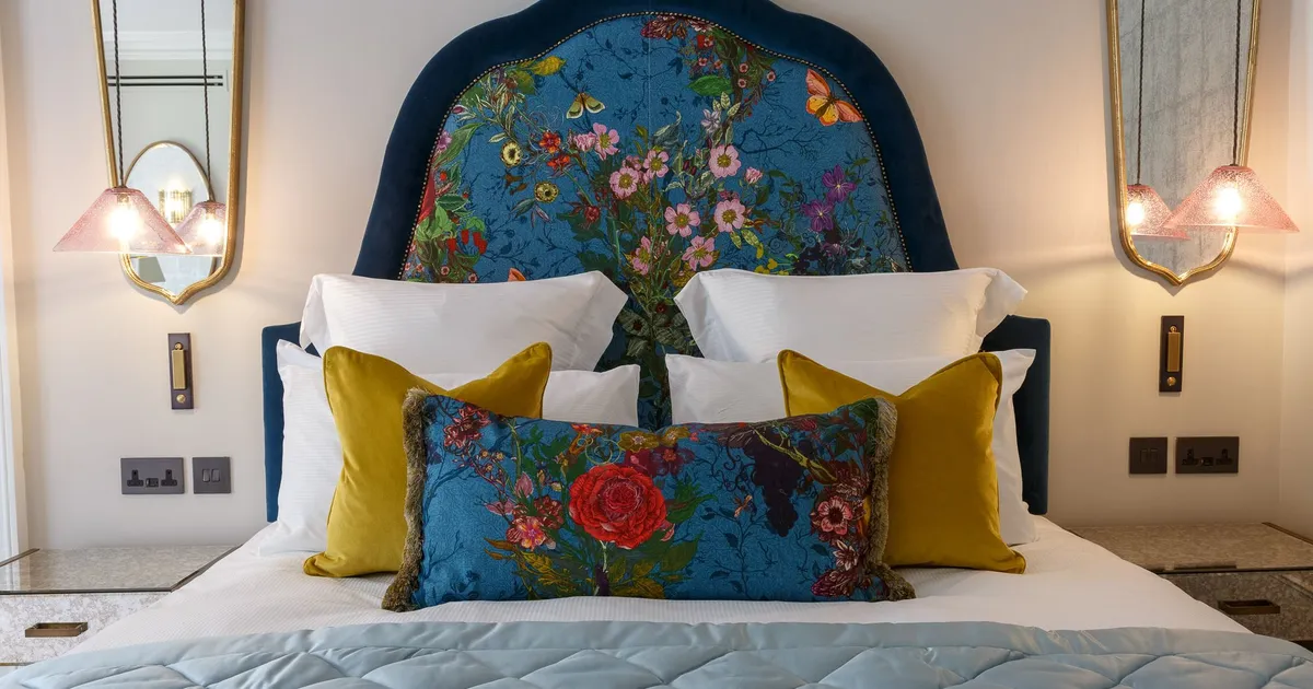 Feature bedroom Delphinium's blue floral headboard, colourful pillows, and modern bedside lighting.