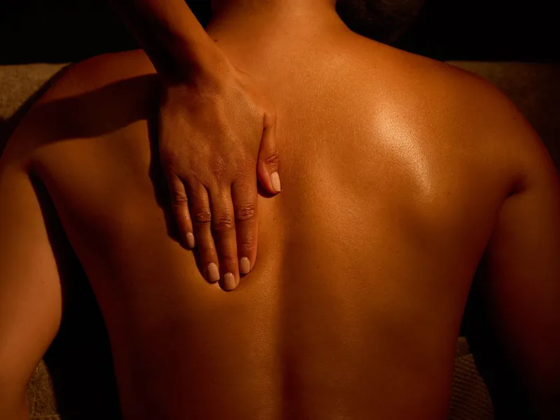 Person receiving a back massage with a hand placed on their back