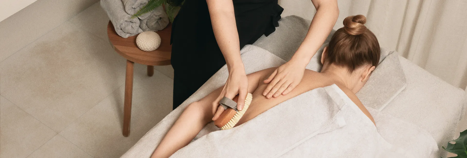 Person receiving a back massage with a dry brush at a spa