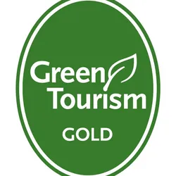Green Tourism Gold award logo featuring a green oval with white text and a leaf symbol.