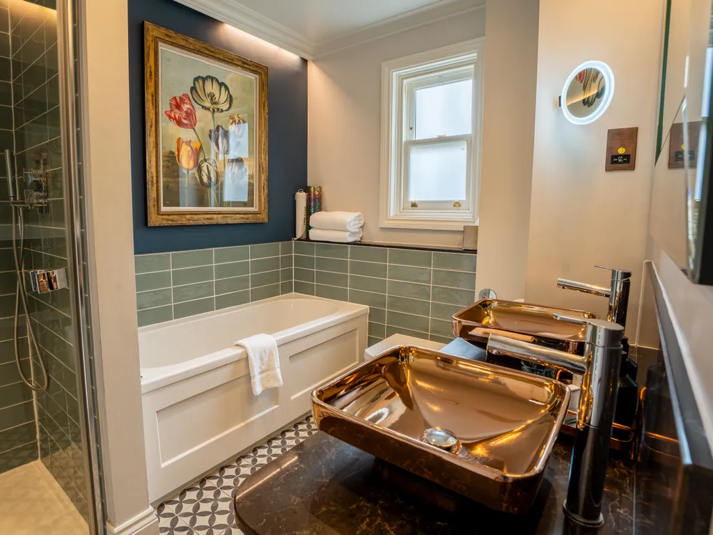 Stylish bathroom with walk-in shower, bath, teal wall tiles and metallic vessel sinks