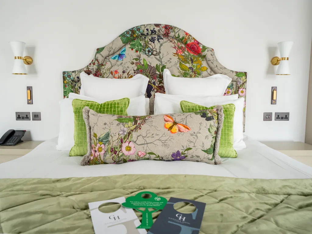Elegant bedroom with a floral upholstered headboard, white bedding and green accent cushions