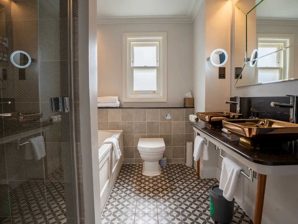 Stylish modern bathroom with walk-in shower, bath, patterned floor tiles and double copper basins