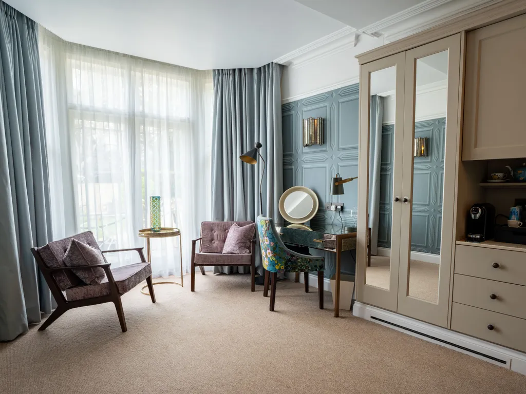 Elegant bedroom seating area with bay window, dressing table, mirrored wardrobe and tea station