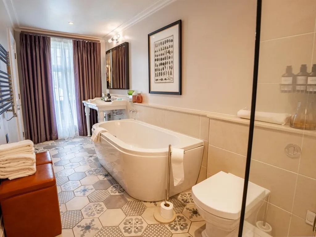 Elegant bathroom with a freestanding bath, patterned tiled floor, shower enclosure and vanity sink