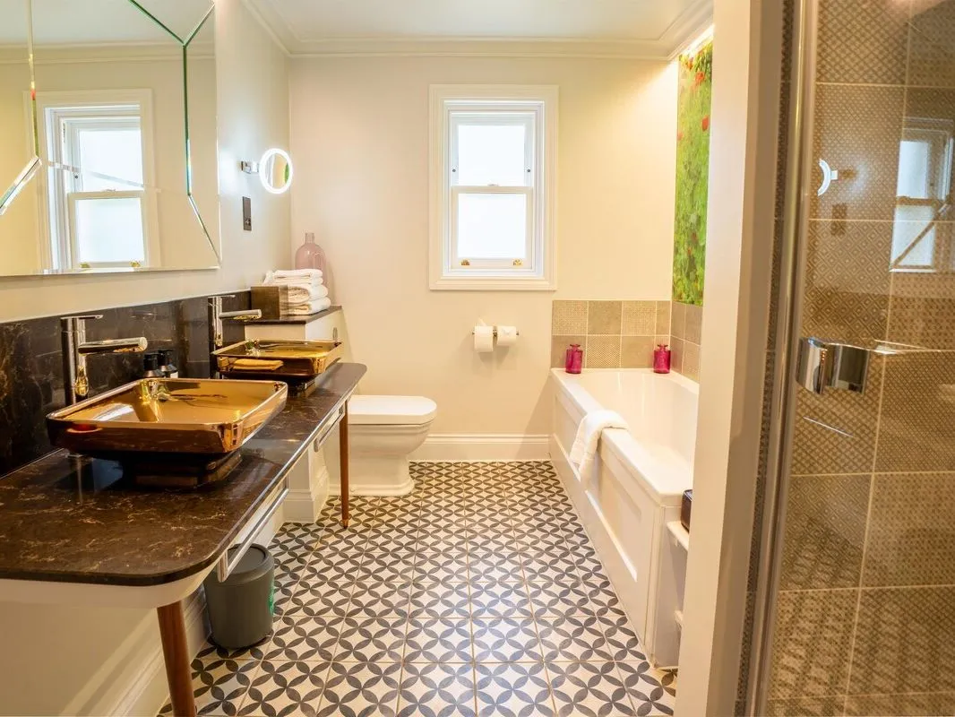 Stylish modern bathroom with double vessel sinks, patterned floor tiles, bath and walk-in shower