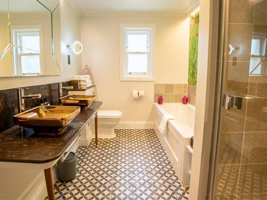 Stylish modern bathroom with double vessel sinks, patterned floor tiles, bath and walk-in shower