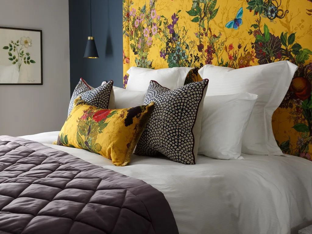 Stylish bedroom with a mustard yellow floral headboard, white bedding and patterned cushions