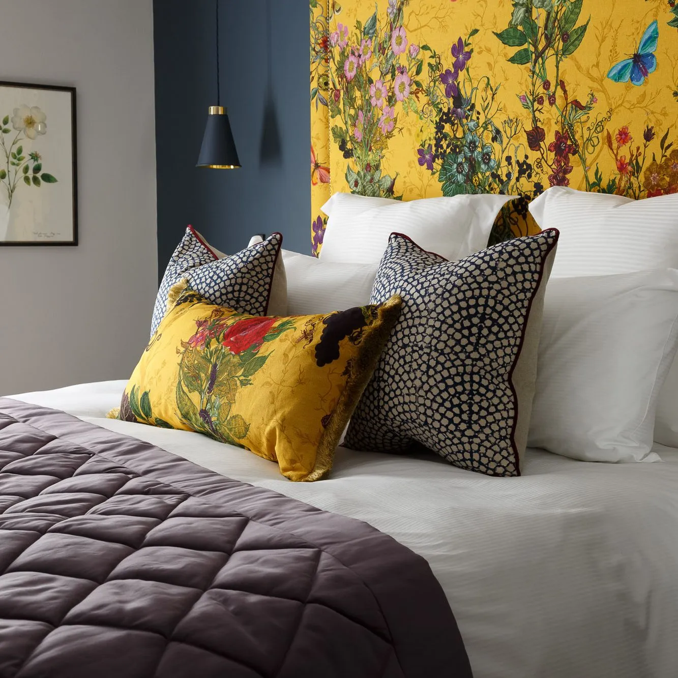 Stylish bedroom with a mustard yellow floral headboard, white bedding and patterned cushions