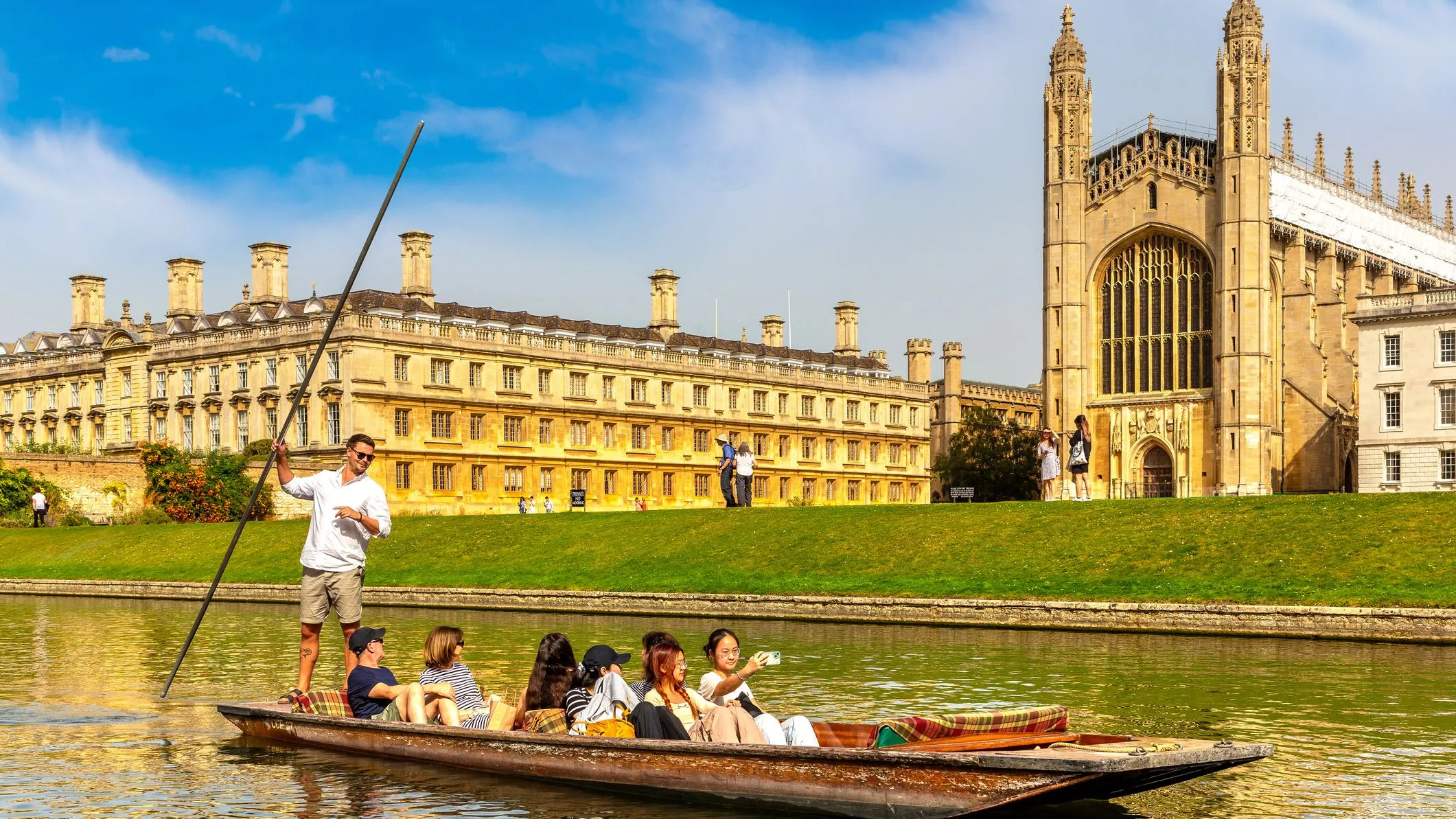 People punting on the River Cam beside King’s College Chapel in Cambridge on a bright sunny day.