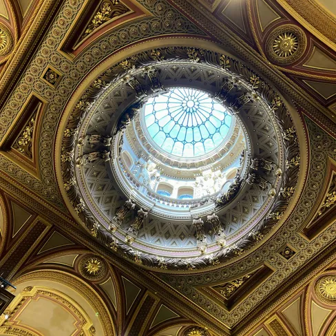Ornate gilded ceiling with a circular skylight and intricate decorative mouldings