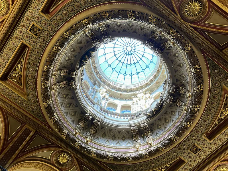 Ornate gilded ceiling with a circular skylight and intricate decorative mouldings