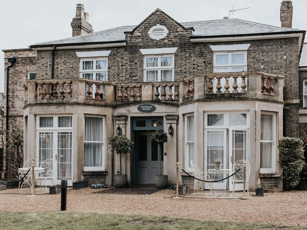 Front exterior of Gresham House, a traditional brick building with stone balconies and white garden furniture.