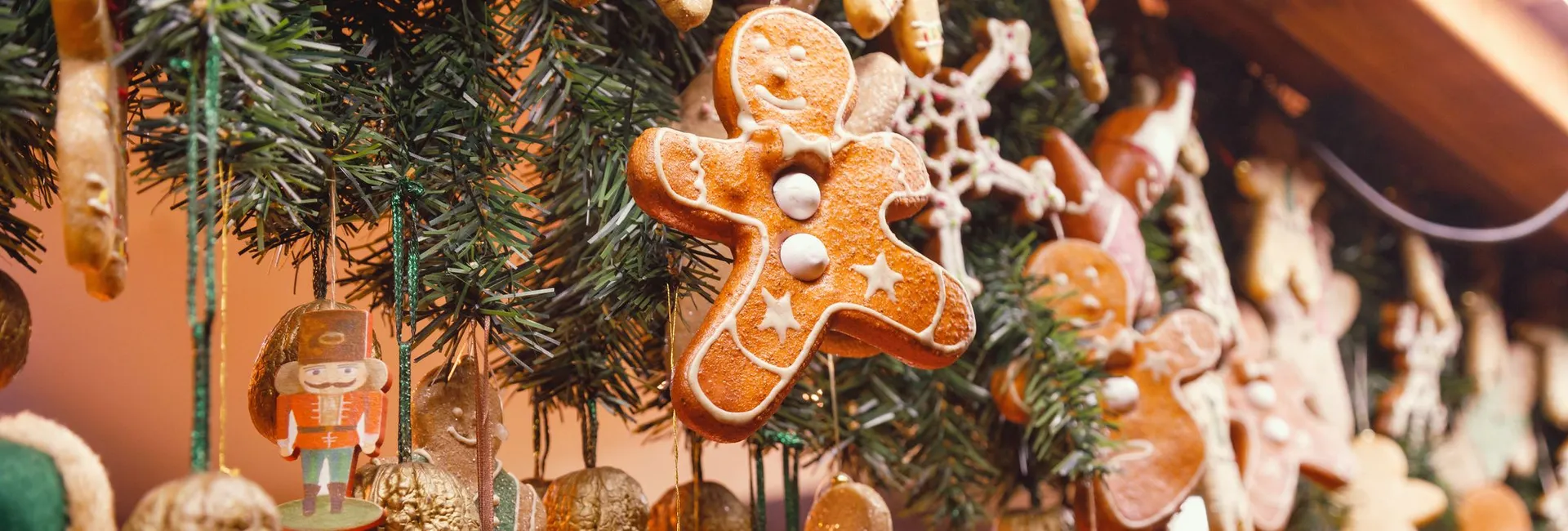 Gingerbread biscuit ornaments and festive decorations hanging from a Christmas tree display