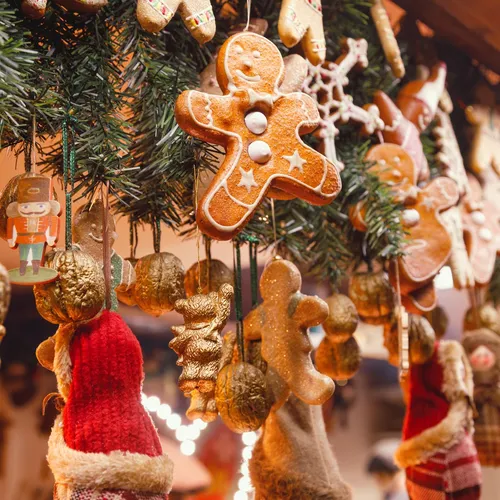 Gingerbread biscuit ornaments and festive decorations hanging from a Christmas tree display