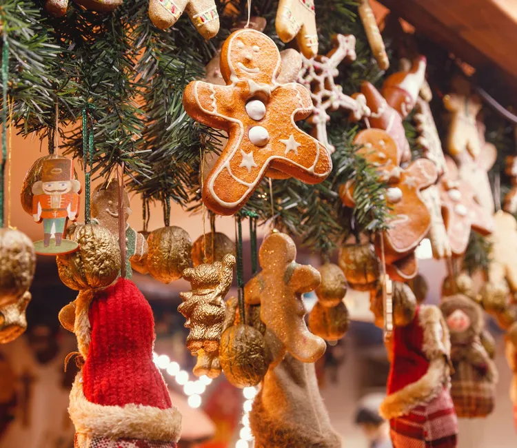 Gingerbread biscuit ornaments and festive decorations hanging from a Christmas tree display