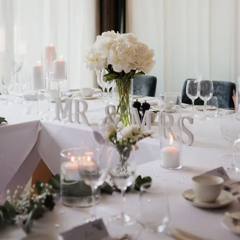 Elegant wedding table with white flowers, candles and freestanding MR & MRS letters