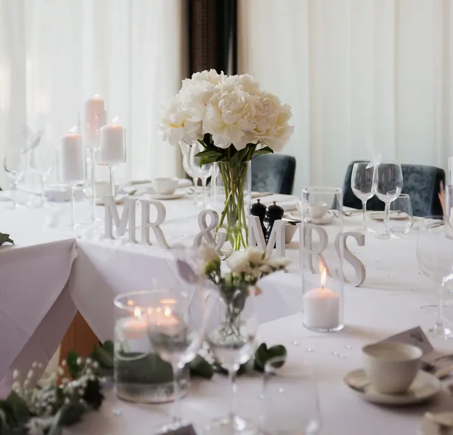 Elegant wedding table with white flowers, candles and freestanding MR & MRS letters