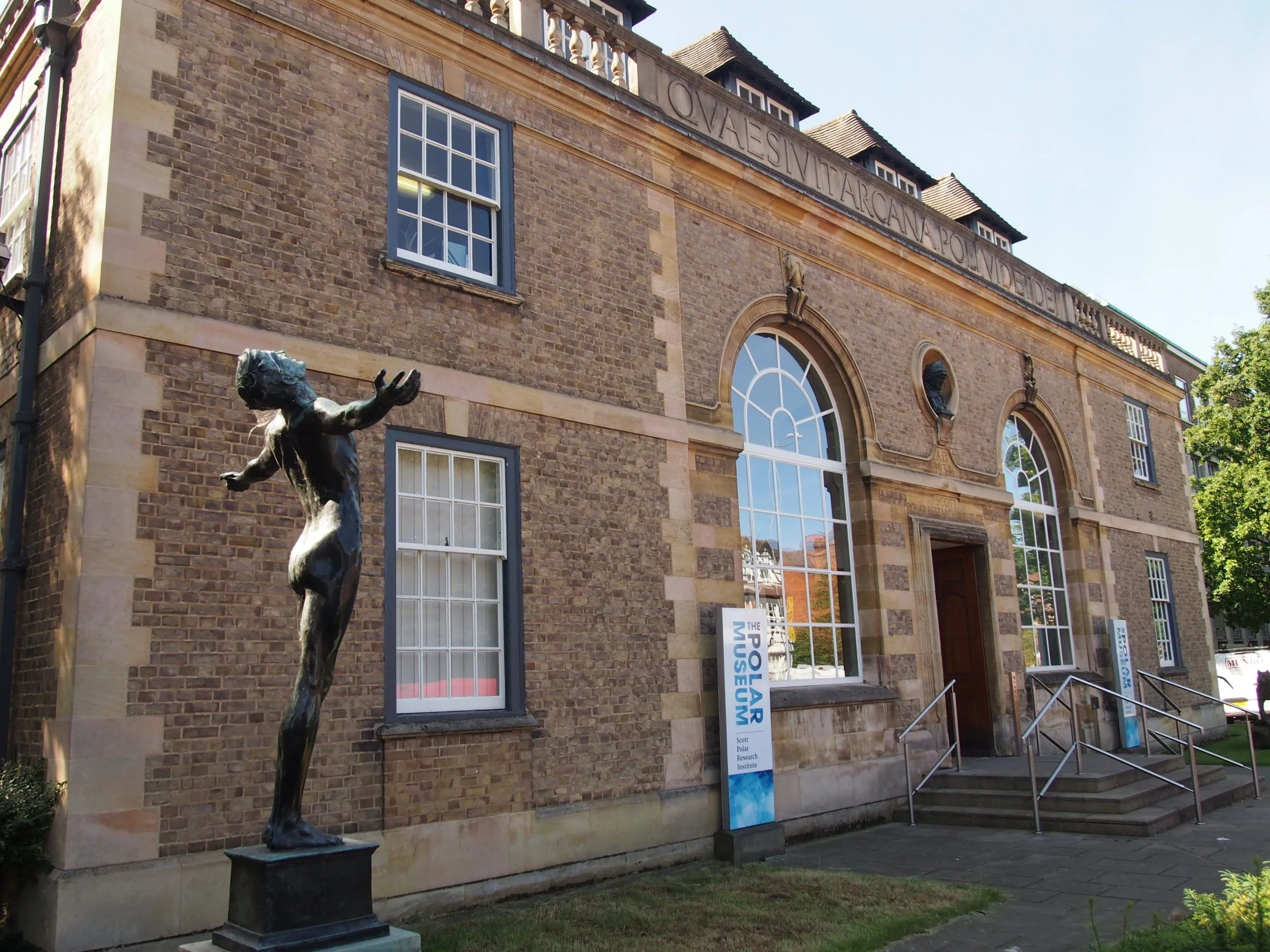 Exterior view of the Scott Polar Research Institute with a bronze statue outside.