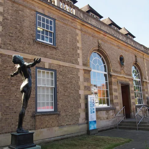 Exterior view of the Scott Polar Research Institute with a bronze statue outside.
