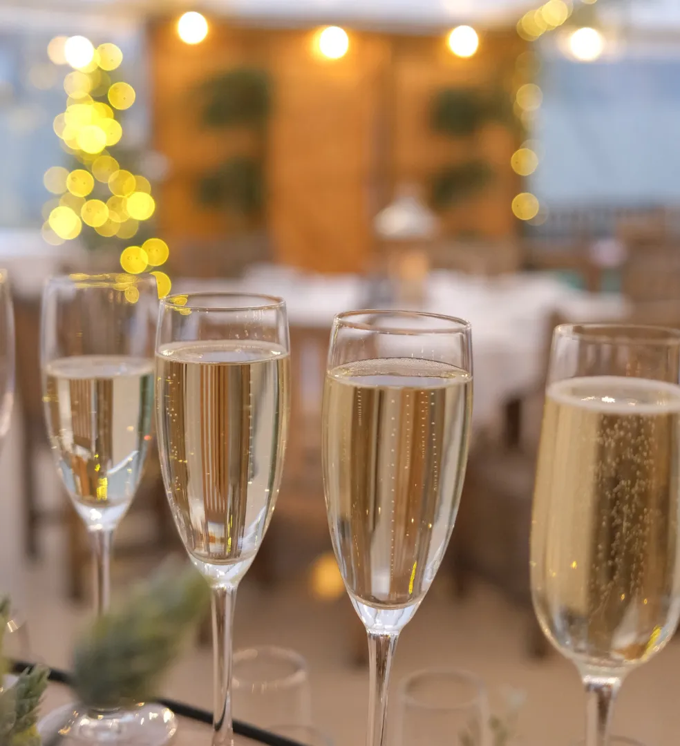Close-up of champagne glasses with bubbles, blurred festive lights in the background