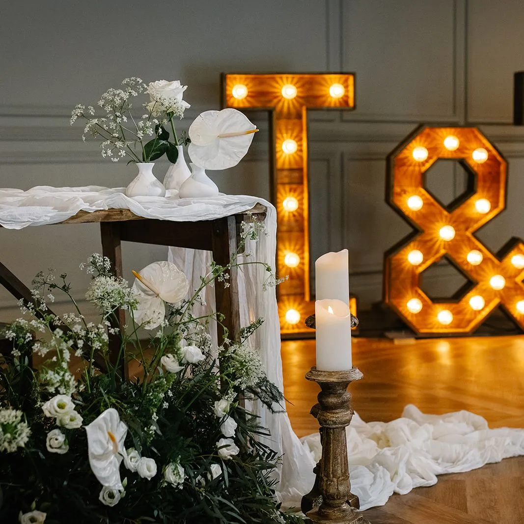 Rustic wedding table styling with white flowers, candles and illuminated T & T letters