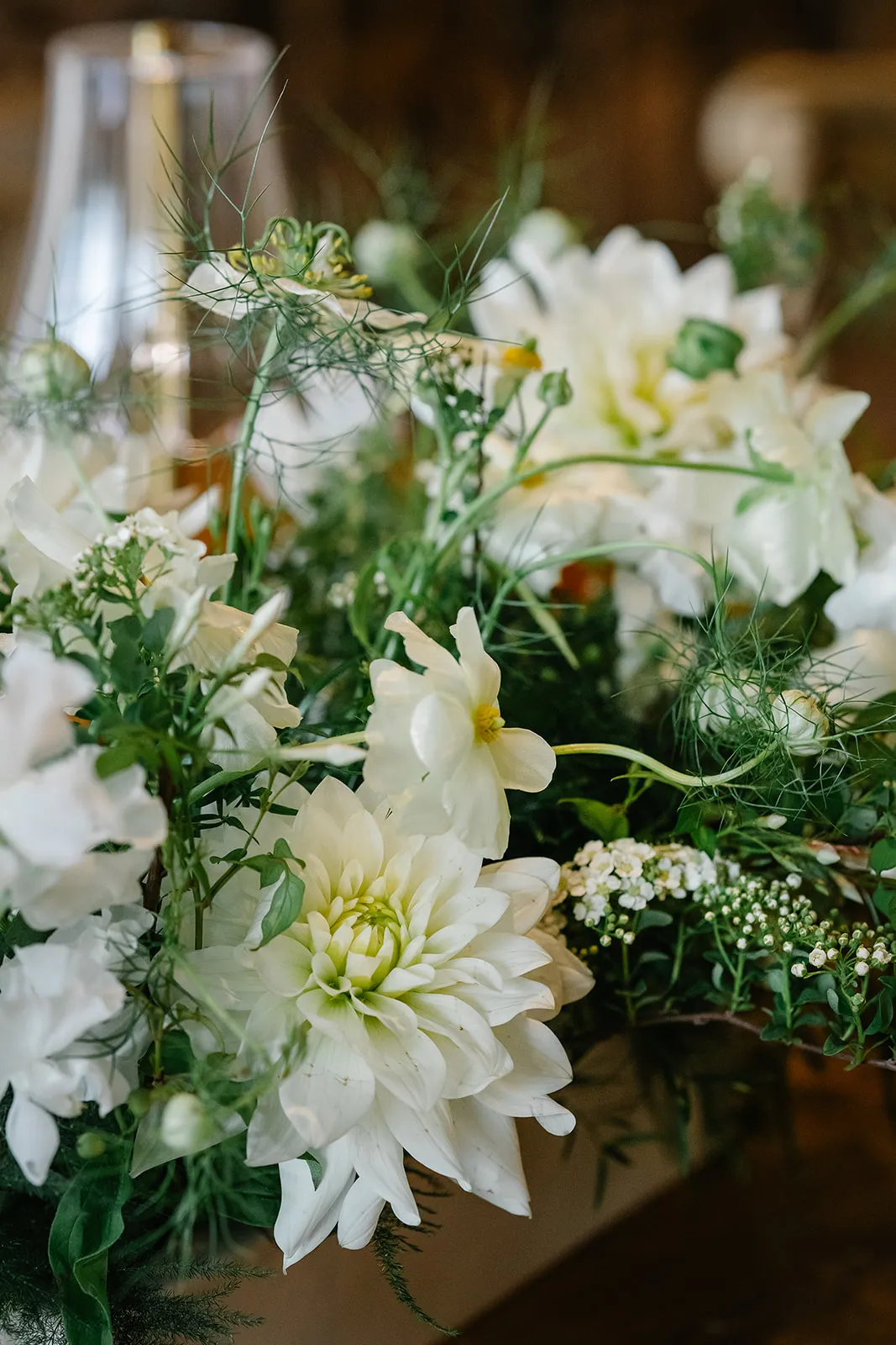 Close-up of an elegant white floral arrangement with soft greenery on a table indoors