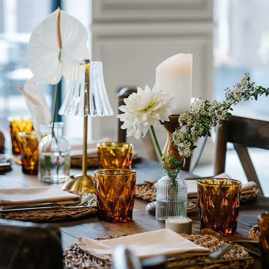 Elegantly dressed dining table with amber glassware, white flowers and candlelight in a softly lit restaurant