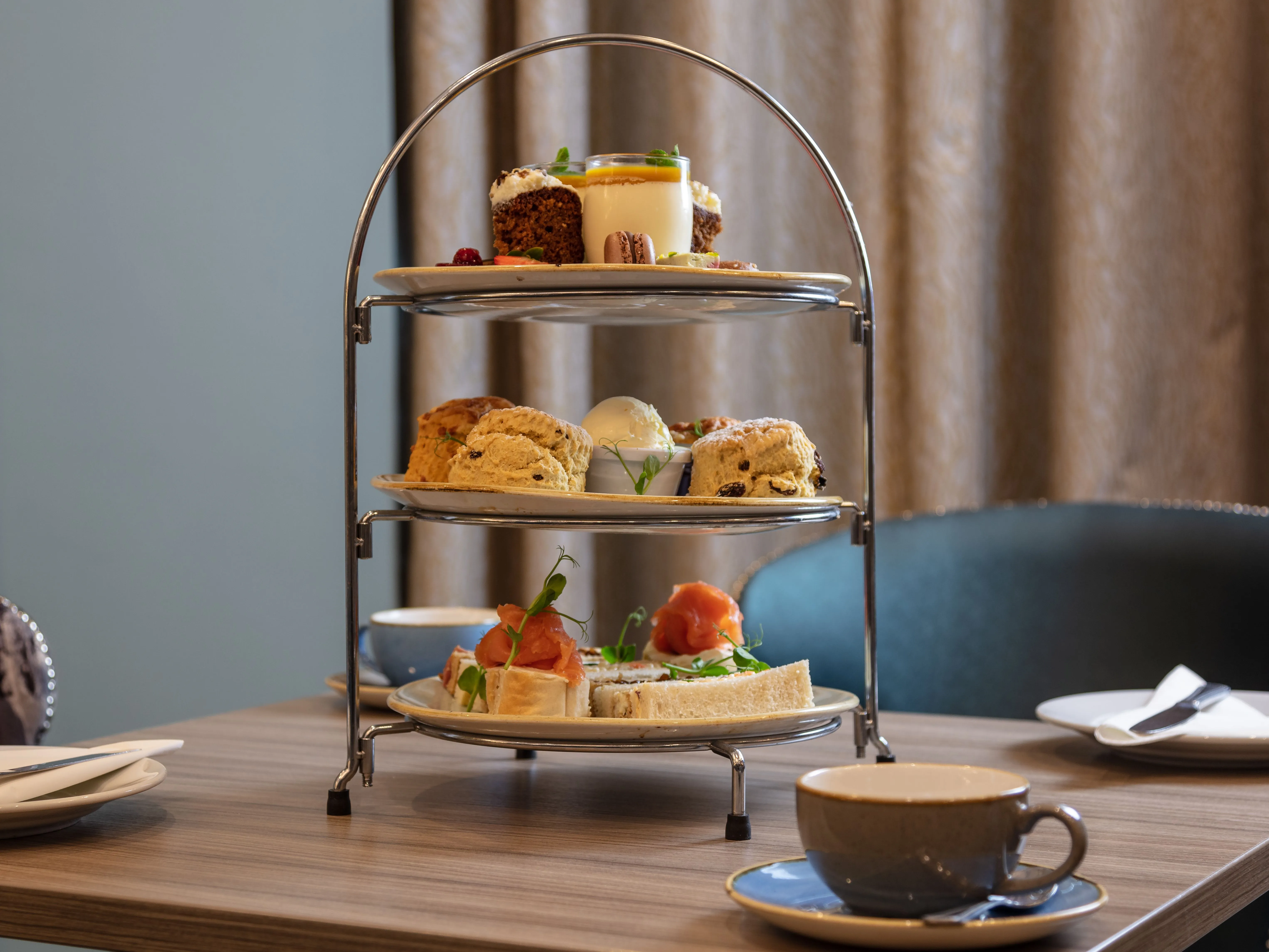 Three-tier afternoon tea stand with finger sandwiches, scones and sweet treats on a table at Holiday Inn Newcastle Gosforth Park