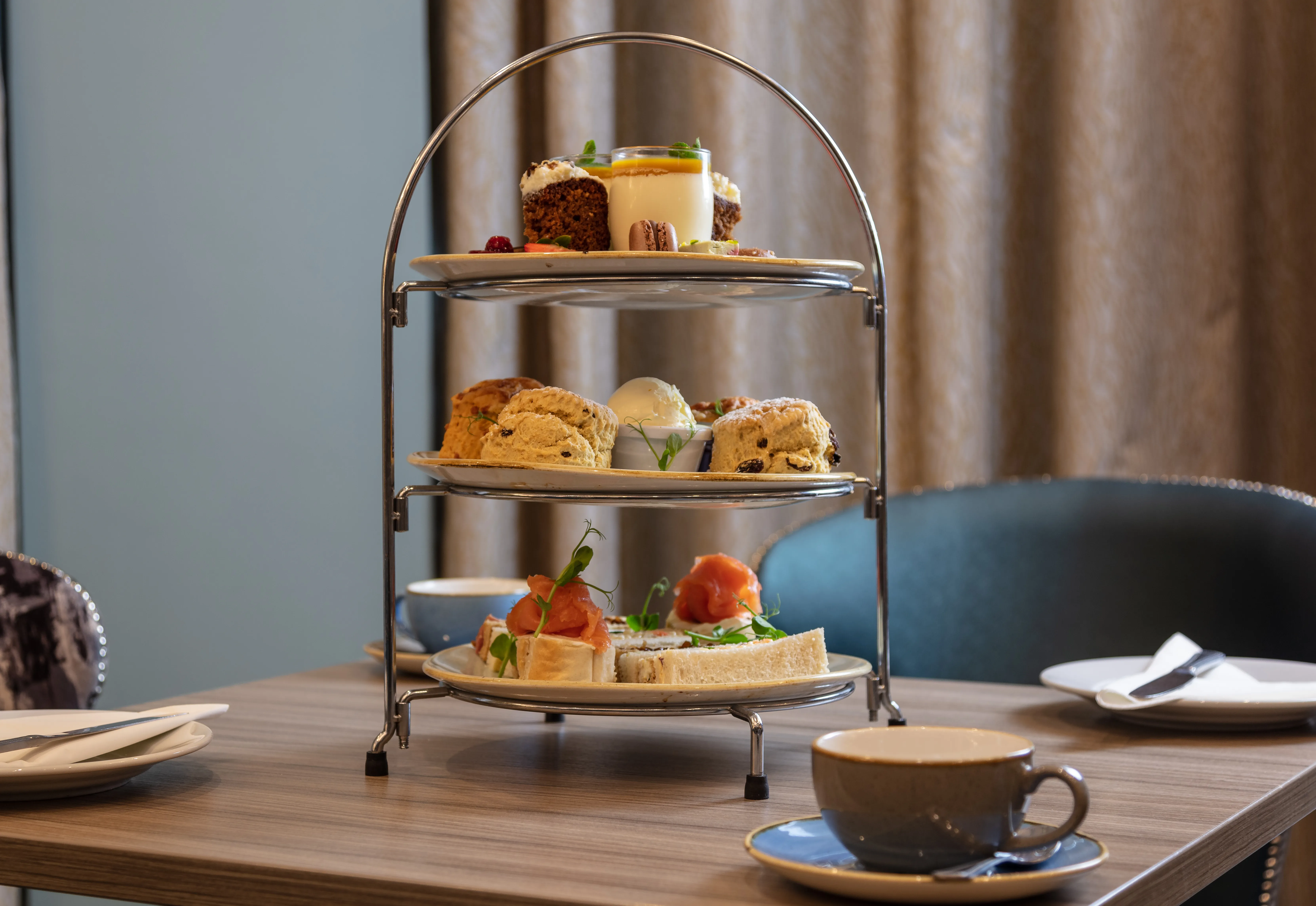Three-tier afternoon tea stand with finger sandwiches, scones and sweet treats on a table at Holiday Inn Newcastle Gosforth Park