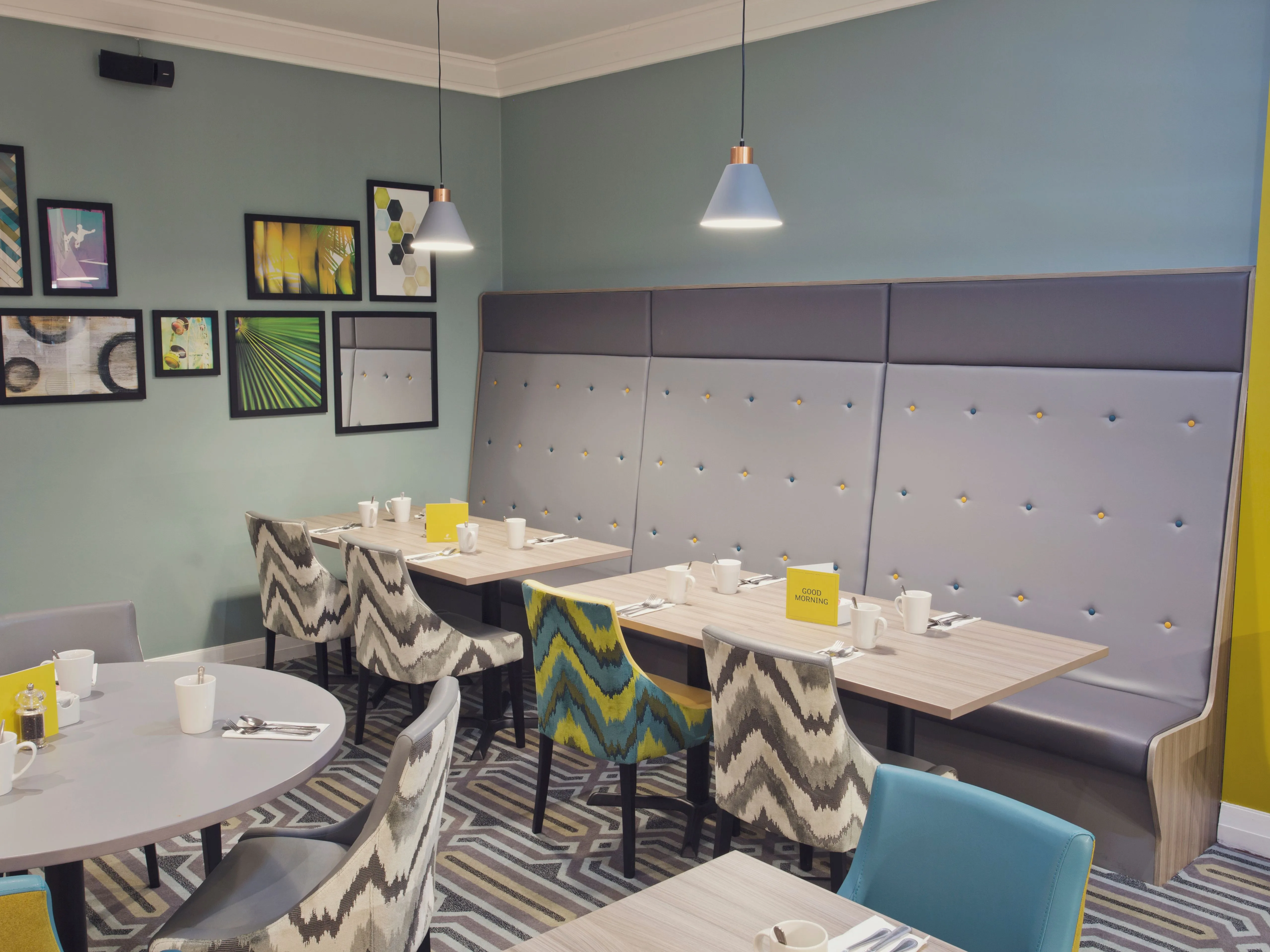 Modern restaurant seating area at Holiday Inn Newcastle Gosforth Park with patterned chairs, booth seating and framed wall art