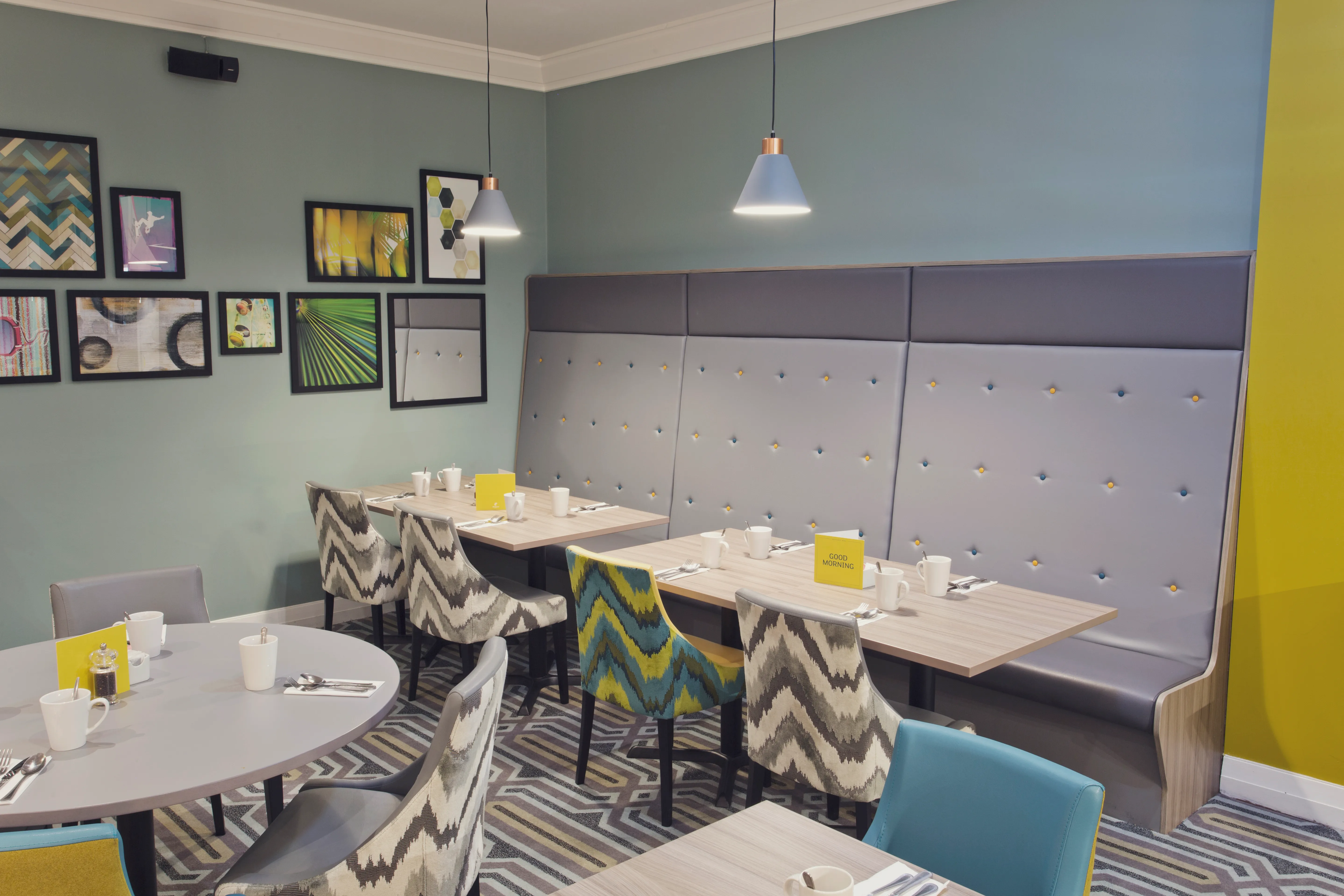 Modern restaurant seating area at Holiday Inn Newcastle Gosforth Park with patterned chairs, booth seating and framed wall art