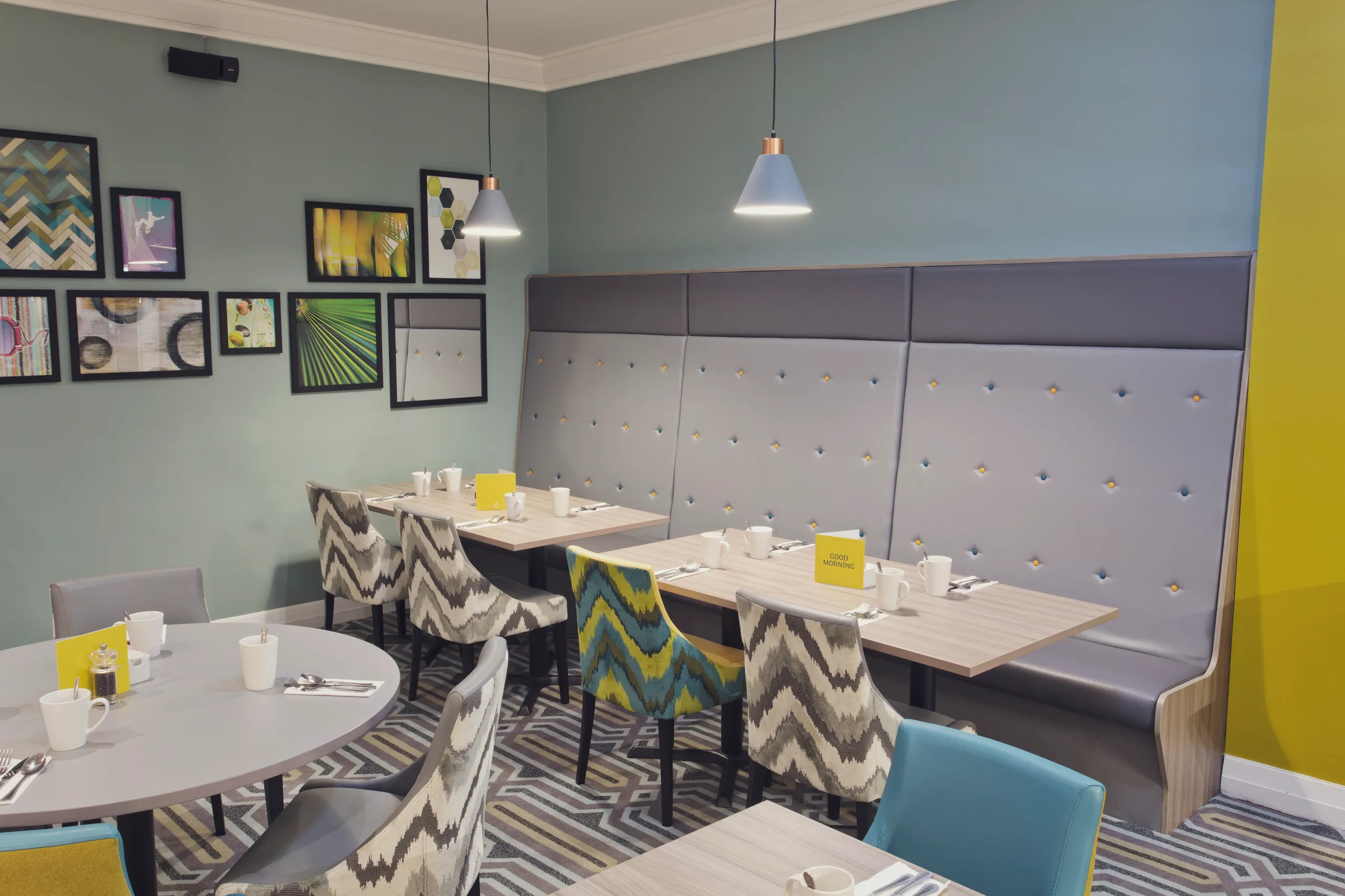 Modern restaurant seating area at Holiday Inn Newcastle Gosforth Park with patterned chairs, booth seating and framed wall art
