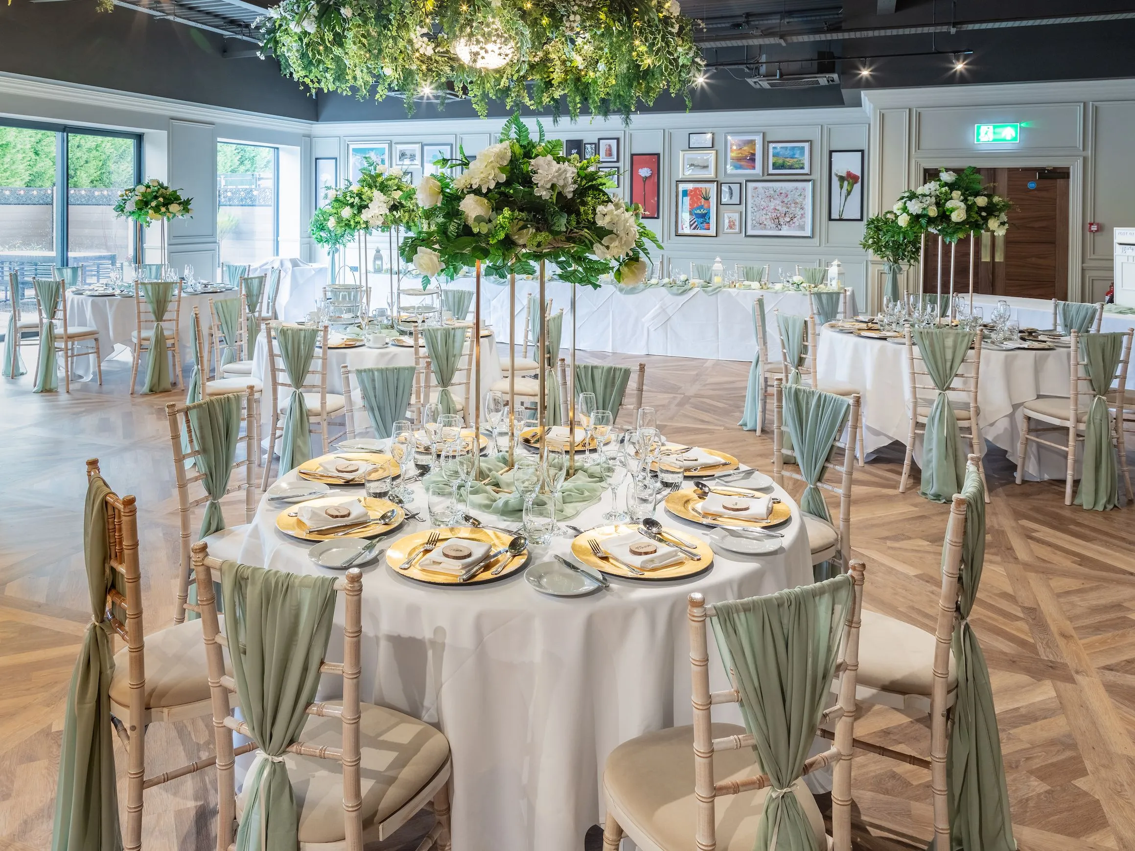 Elegant wedding reception room at Holiday Inn with round tables, white floral centrepieces and sage green chair drapes