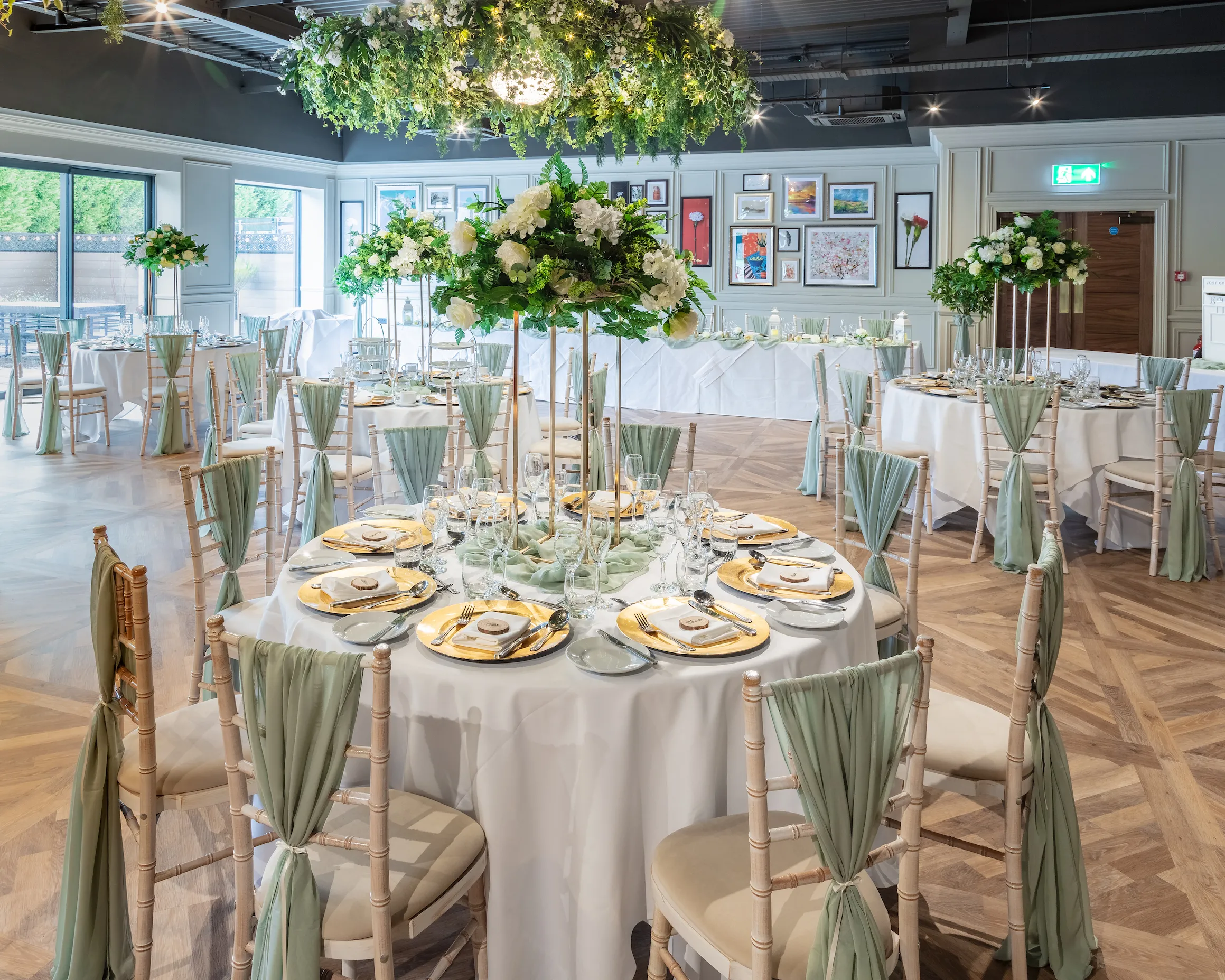 Elegant wedding reception room at Holiday Inn with round tables, white floral centrepieces and sage green chair drapes