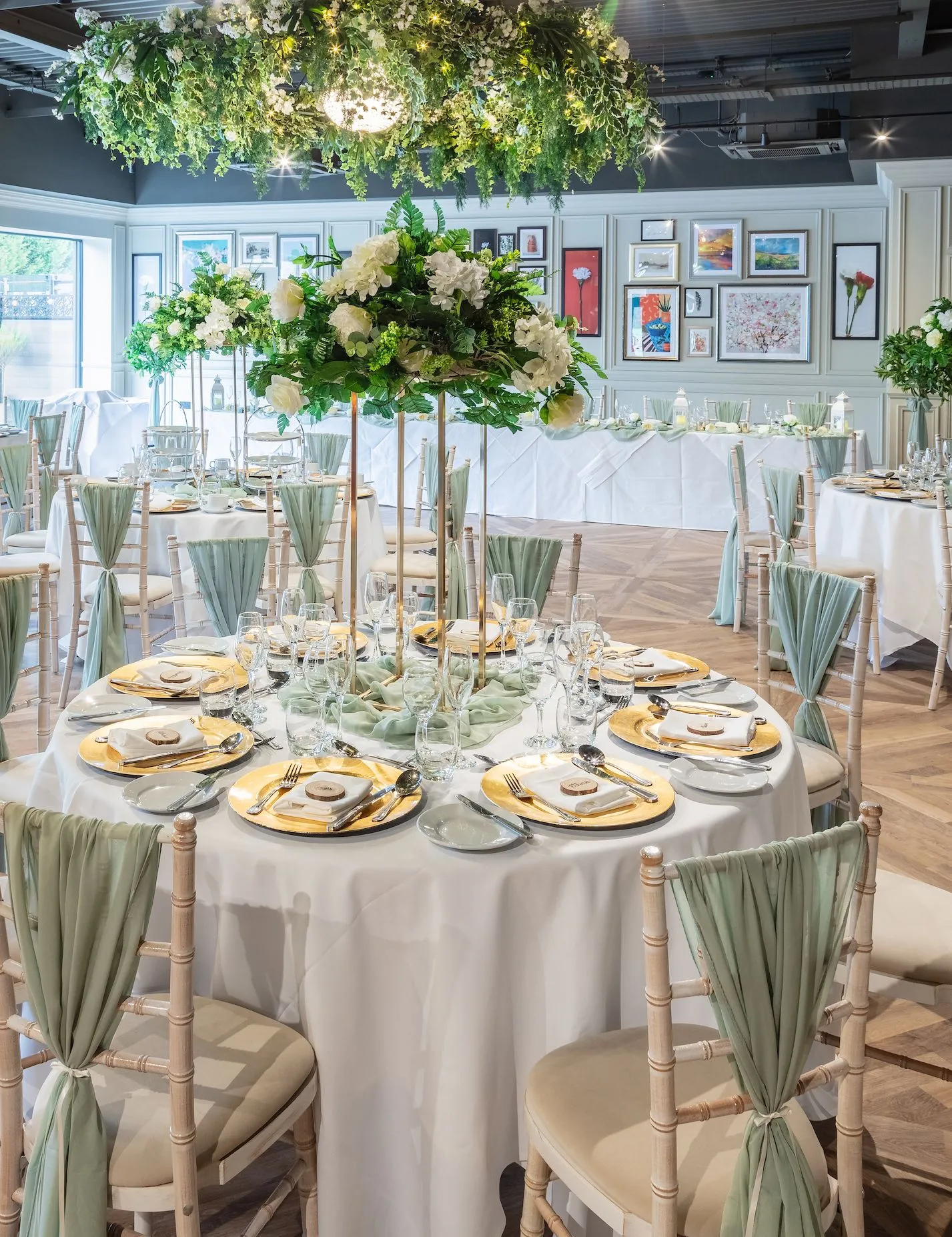 Elegant wedding reception room at Holiday Inn with round tables, white floral centrepieces and sage green chair drapes