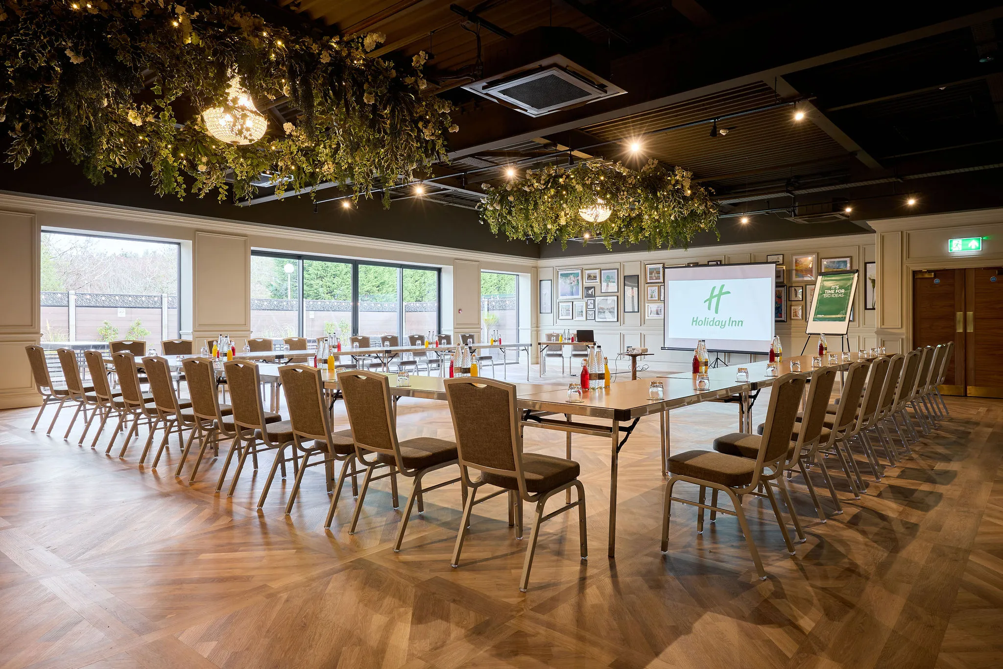 Elegant Holiday Inn meeting room arranged in a U-shape with chairs, presentation screen and floral ceiling decorations
