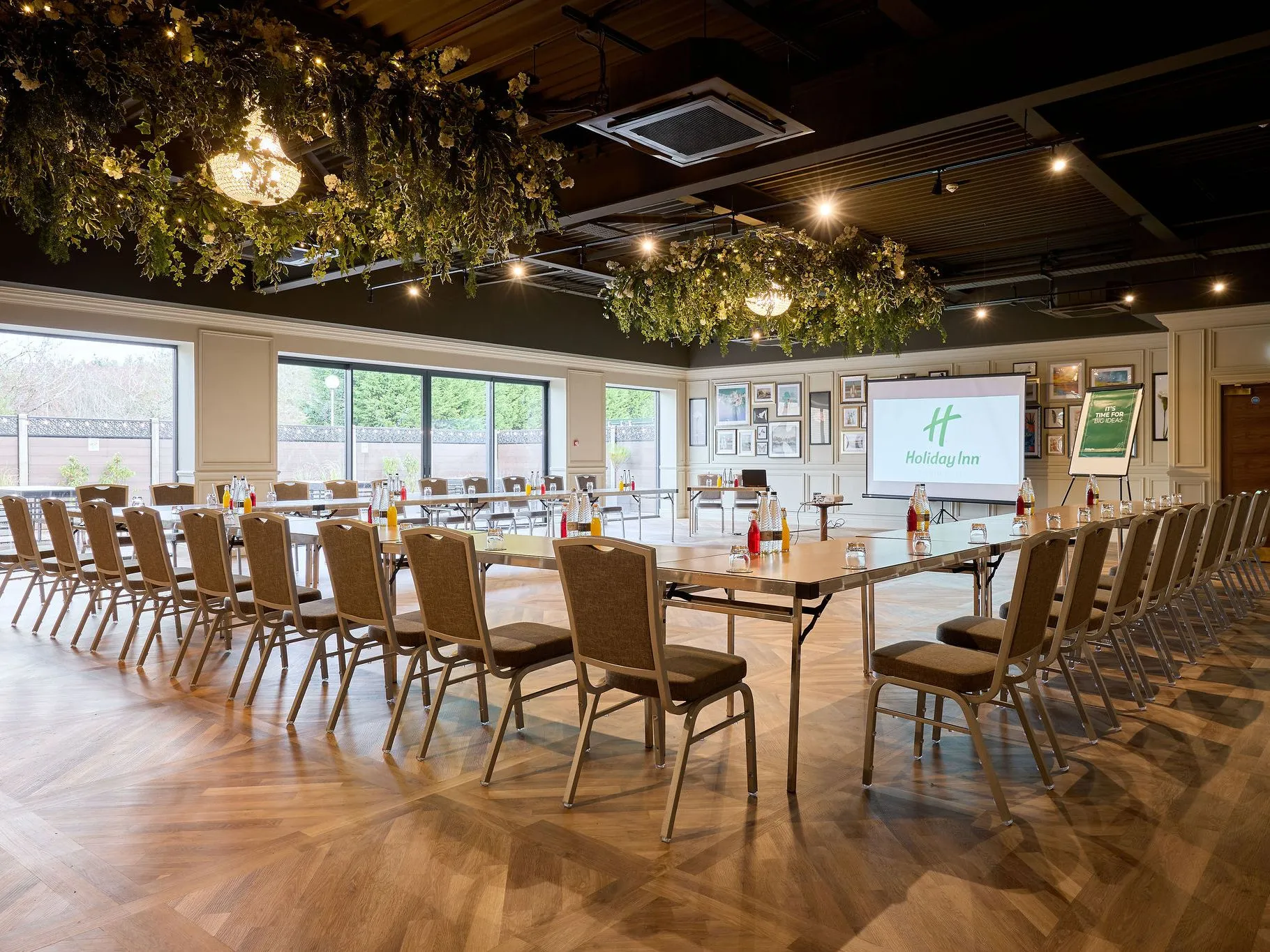Elegant Holiday Inn meeting room arranged in a U-shape with chairs, presentation screen and floral ceiling decorations