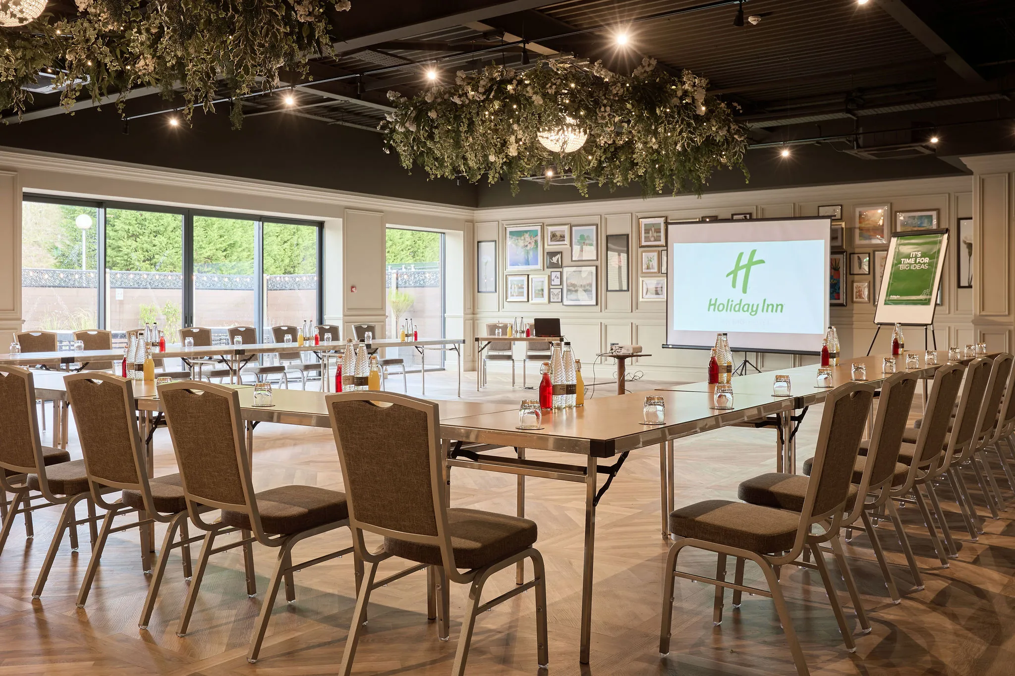 Meeting room at Holiday Inn with U-shaped conference layout, projector screen and floral ceiling décor